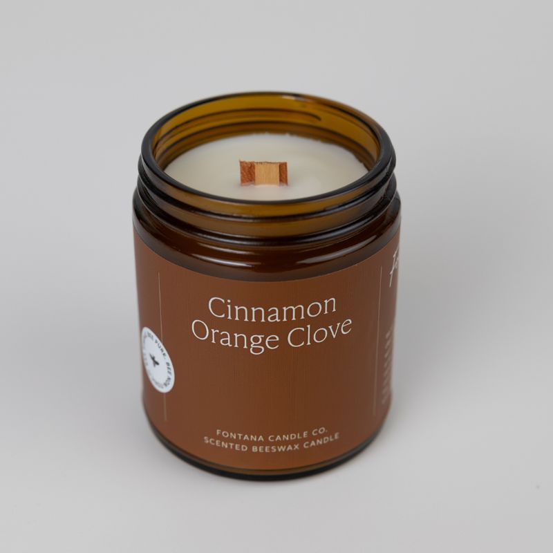 Candle in a brown jar labeled 'Cinnamon Orange Clove' on a white background