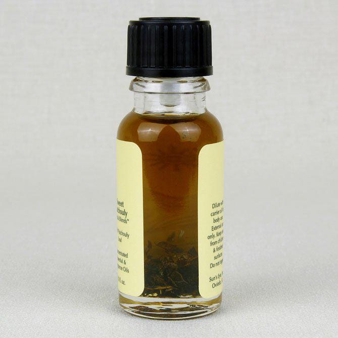 Small glass bottle of sweet patchouly oil with a black cap and yellow label on a light gray background