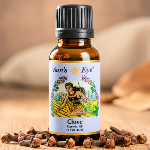 Bottle of Sun's Eye Clove essential oil with cloves on a wooden surface