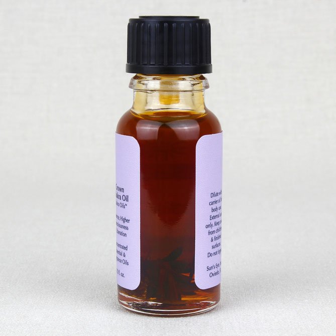 Small glass bottle of crown chakra oil with a black cap and a white label on a light gray background