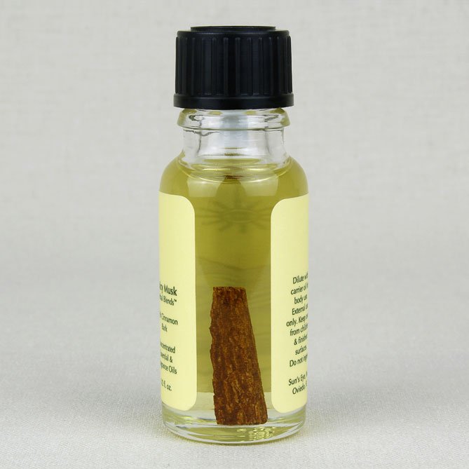 Small glass bottle with a black cap and cinnamon stick on a light gray background