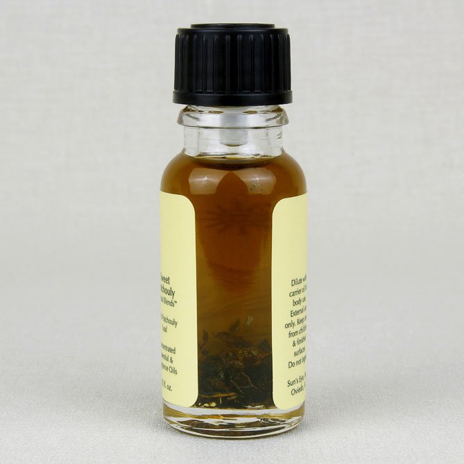 Small glass bottle of sweet patchouly oil with a black cap and yellow label on a light gray background